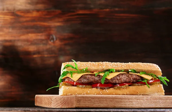 Grillezett szaftos bagett szendvics szelettel és friss zöldségekkel fából készült háttérrel. Szendvics menü — Stock Fotó