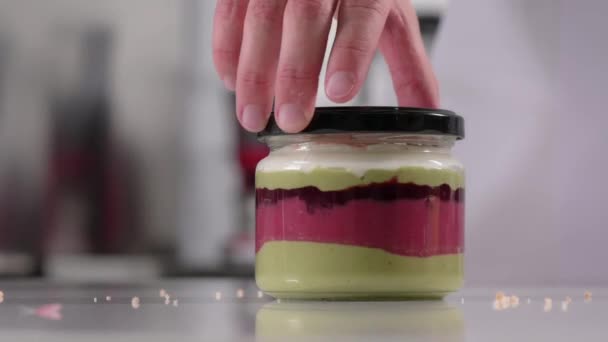 Pastry chef prepares layered creamy dessert in jar, parfait. Dessert preparation process. Video series — Stock Video
