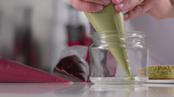 Pastry chef prepares layered creamy dessert in jar, parfait. Dessert preparation process. Video series — Stock Video