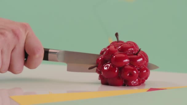 Pastry chef cuts chokolat red mini cake on colored green background. Cake filling — Stock Video