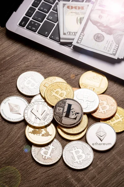 Montón de monedas criptomoneda y pila de dólares en la mesa cerca de la computadora portátil. Bitcoin y otras criptomonedas — Foto de Stock