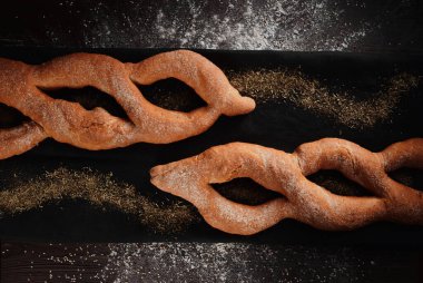 Çavdar ekmeği ve buğday unundan örülmüş çörekler ve siyah arka planda buğday unları. Üst Manzara. Metin için boşluk