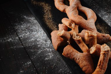 Çavdar ekmeği ve buğday unundan örülmüş çörekler ve siyah arka planda buğday unları. Üst Manzara. Metin için boşluk