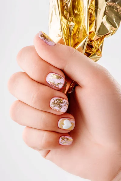 Mulher segurando folha de ouro para manicure. Pregos bem cuidados e mãos suaves esfolam a larga bandeira. Tratamento de beleza. Belas unhas manicure — Fotografia de Stock