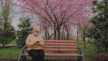 Maskesiz Avrupalı adam parktaki bankta bulaşıcı bir şekilde öksürüyor. Coronavirüs salgını