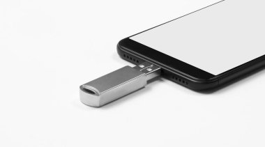Taşınabilir USB bellek beyaz arka planda izole edilmiş cep telefonuna bağlı. Model.