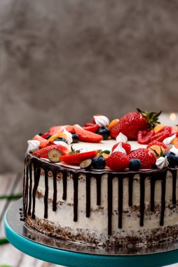 Taze böğürtlenli güzel bir pasta ve beyaz ahşap arka plandaki pasta standına çikolata damlaları. Metin için boşluk