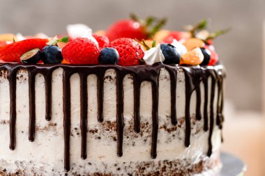 Taze böğürtlenli güzel bir pasta ve beyaz ahşap arka plandaki pasta standına çikolata damlaları. Metin için boşluk