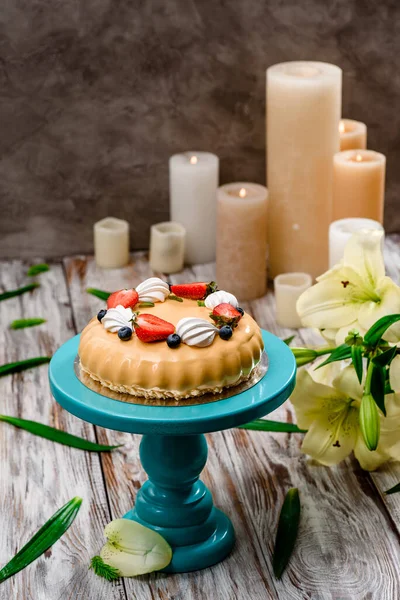 Prachtige taart met beige glazuur versierd met verse bessen op een taart staan op een houten achtergrond. Ruimte voor tekst — Stockfoto