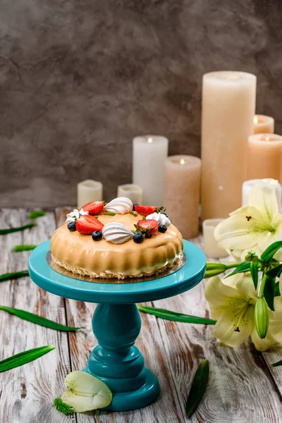 Prachtige taart met beige glazuur versierd met verse bessen op een taart staan op een houten achtergrond. Ruimte voor tekst — Stockfoto