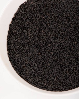 Beyaz bir zeminde izole edilmiş siyah susam tohumları..