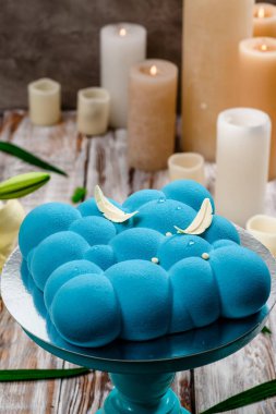 Beyaz ahşap bir arka planda pasta standında mavi kremalı pasta. Metin için boşluk