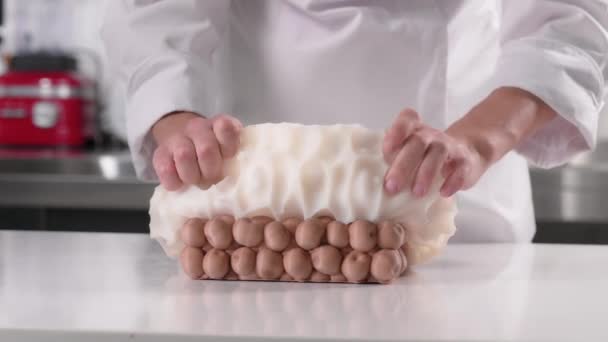 Chef pâtissier gratte le gâteau congelé dans un moule en silicone pour le vitrage. Processus de fabrication des desserts. — Video