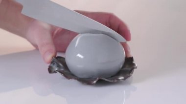 Pasta şefi tatlıyı beyaz arka planda gri jöleli inci şeklinde keser. Kapat.