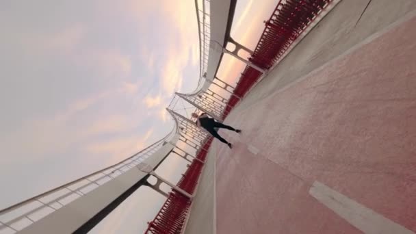 Jovem branco Homem de uniforme esporte preto fazendo aquecimento antes de correr ponte pedonal ao amanhecer — Vídeo de Stock