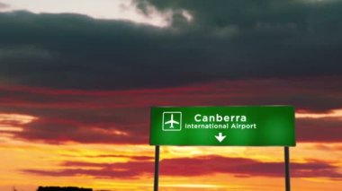 Canberra, Avustralya 'ya inen uçak silueti. Havaalanı yön tabelasıyla ve arka planda gün batımıyla şehre vardık. Trip ve ulaşım kavramı.