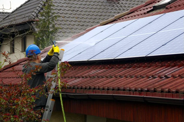 Cleaning solar panels. A man on a ladder cleans and washing a photovoltaic installation.