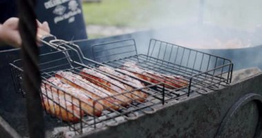 Ağır çekim. Sosisler açık ateşte kızartılıyor, V2 'yi kapatın.