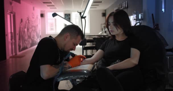 Een tatoeëerder maakt een tatoeage op een arm, werkt in de studio. Close-up weergave Slow motion V3 — Stockvideo