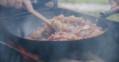 Yakın çekim taze sebzeler açık havada açık ateşte tavada pişirilir. Yavaş çekim