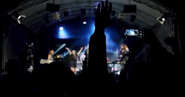 Блакитна силует людей тримає руки з телефоном в руці і знімає відео на концерті. Повільний рух V9 — стокове відео