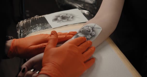 Tatuagem artista coloca uma imagem em uma mão de mulheres jovens, processo de criação de uma tatuagem. Visão de close-up Movimento lento V3 — Vídeo de Stock