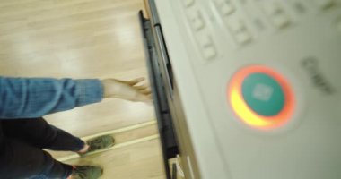 Kapatın. Ofisteki yazıcıya kağıt koyan bir kadının elleri. ve düğmeye basıyor.