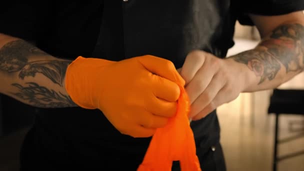 Tattoo artist wears sterile orange gloves, Close up — Stock Video