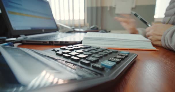 Close up of woman hands working on laptop and calculator, counting checks. — Stock Video