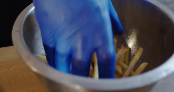 Шеф-повар берет руку в голубых перчатках картофель фри из большого блюда. Закрыть — стоковое видео