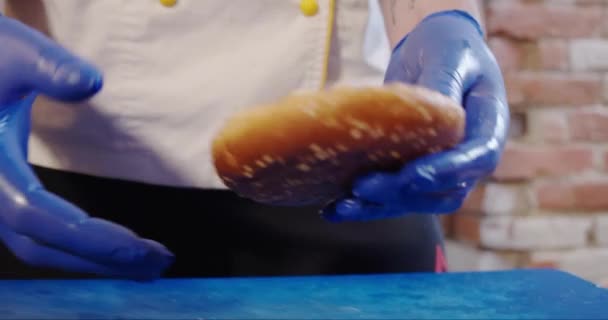 Chiudete. Le mani di cuoco mettono il pane superiore su un hamburger. . Rallentatore — Video Stock