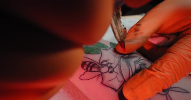 Tatueringskonstnär ritar en bild på en ung kvinnas hand, processen att skapa en tatuering med blått ljus. Långsam rörelse Närbild — Stockvideo