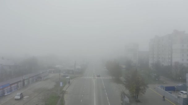 Luftaufnahme von oben, wie Autos über eine nebelbedeckte Straße in einem Vorort fahren. — Stockvideo