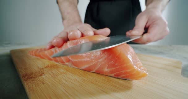 Chef comienza a cortar con un cuchillo de pescado a la tabla de madera. Primer plano, cámara lenta — Vídeos de Stock