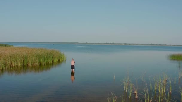 Αεροφωτογραφία τηλεκατευθυνόμενου. Ένας άντρας στέκεται στη λίμνη και ψαρεύει το πρωί του καλοκαιριού. — Αρχείο Βίντεο