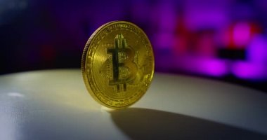 Bir bitcoin para renkli bir arkaplanda döner. Kapat.