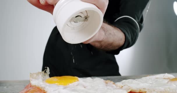 Chiudere aggiungendo sale marino grossolano utilizzando un mulino a sale durante la cottura delle uova. Rallentatore — Video Stock
