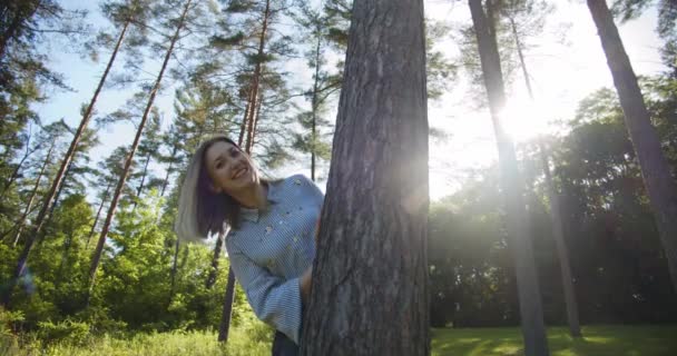 Mujer joven escondida detrás del árbol cubierto. — Vídeo de stock