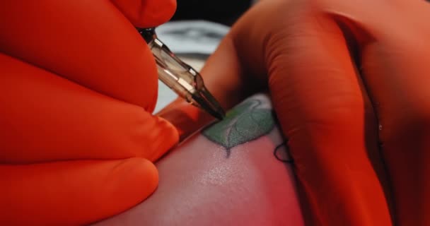 Schuss in Zeitlupe. Extime Close up Tätowierer zeichnet ein Bild auf der Hand einer jungen Frau, der Prozess der Schaffung eines Tattoomit blauem Licht. — Stockvideo