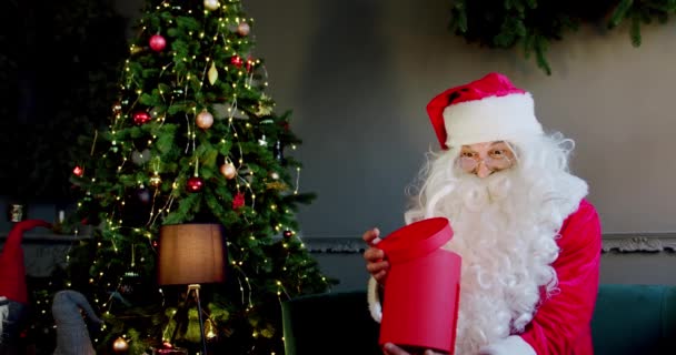 Portret Santa Claus opens magic glowing gift box and looks inside, bright light shines from box. Slow motion — Stock Video