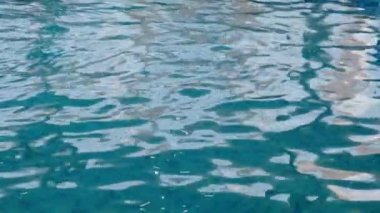 Havuzda saf mavi su ve ışık yansımaları. Ağır çekim. Kapat.