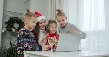 Yılbaşı konsepti, anne ve Noel kostümlü çocukları bilgisayardan online arama yapıyorlar..