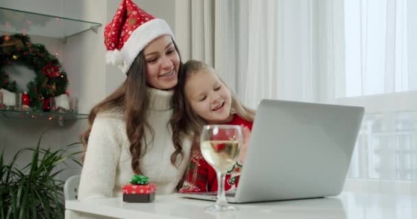 Conceito de Ano Novo, mãe e sua filha em trajes de Natal fazer uma chamada on-line no laptop. — Vídeo de Stock