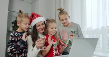 Yeni yıl konsepti, anne ve çocukları Noel kostümü içinde dizüstü bilgisayardan bir arama yapıyorlar..