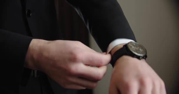 Zakenman of bruidegom in pak doet een horloge om zijn hand. slow motion — Stockvideo