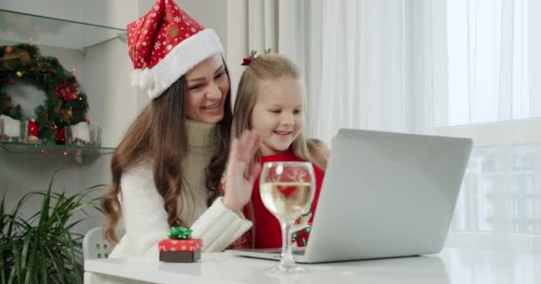 Concepto de Año Nuevo, mamá y su hija en trajes de Navidad hacer una llamada en línea en el ordenador portátil. — Vídeo de stock