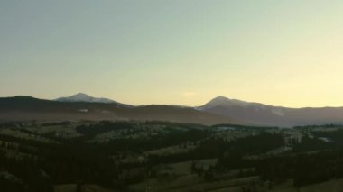 Gün batımında Dağ 'daki ormanın üzerinden geçen hava aracı görüntüsü.