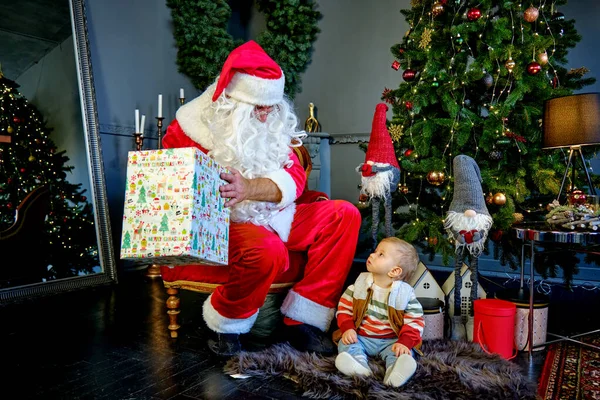 Sevimli küçük çocuk ve Noel Baba hediye kutusunu tutuyorlar ve ona bakıyorlar. Yeni yıl kavramı