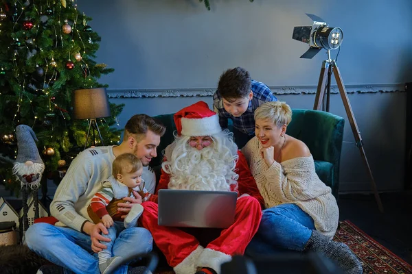 Aile Noel Baba 'yla birlikte kanepede oturup dizüstü bilgisayara bakıyorlar..