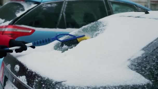 Ženský ruce čistí auto od sněhu štětcem. Auto zakryl sníh. Uzavření pomalého pohybu — Stock video